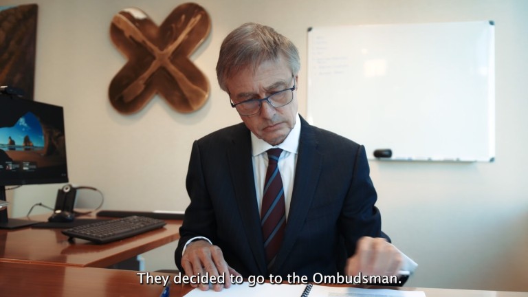 Chief Ombudsman John Allen reading documents at his desk.