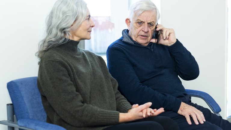 An elderly man speaking on the phone with a look of concentration.